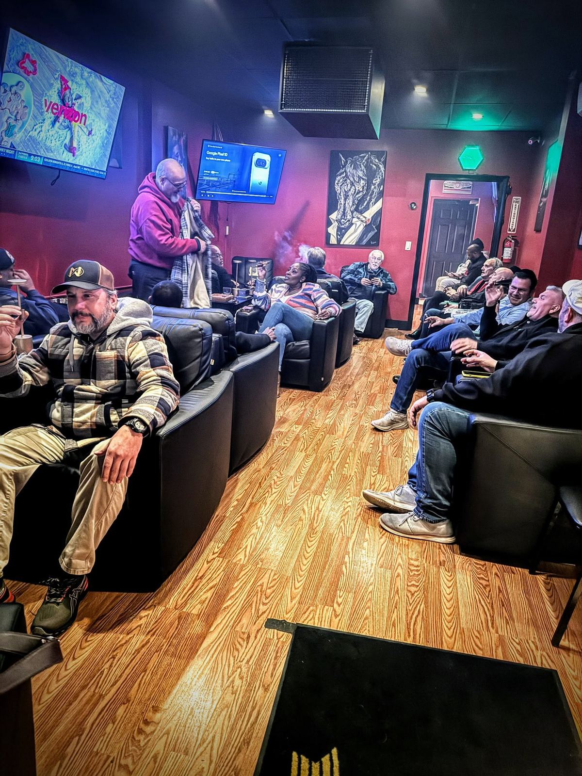 Regulars relaxing in leather chairs in the Mane Street Cigars lounge in Woodbridge, NJ, with a horse painting on the wall